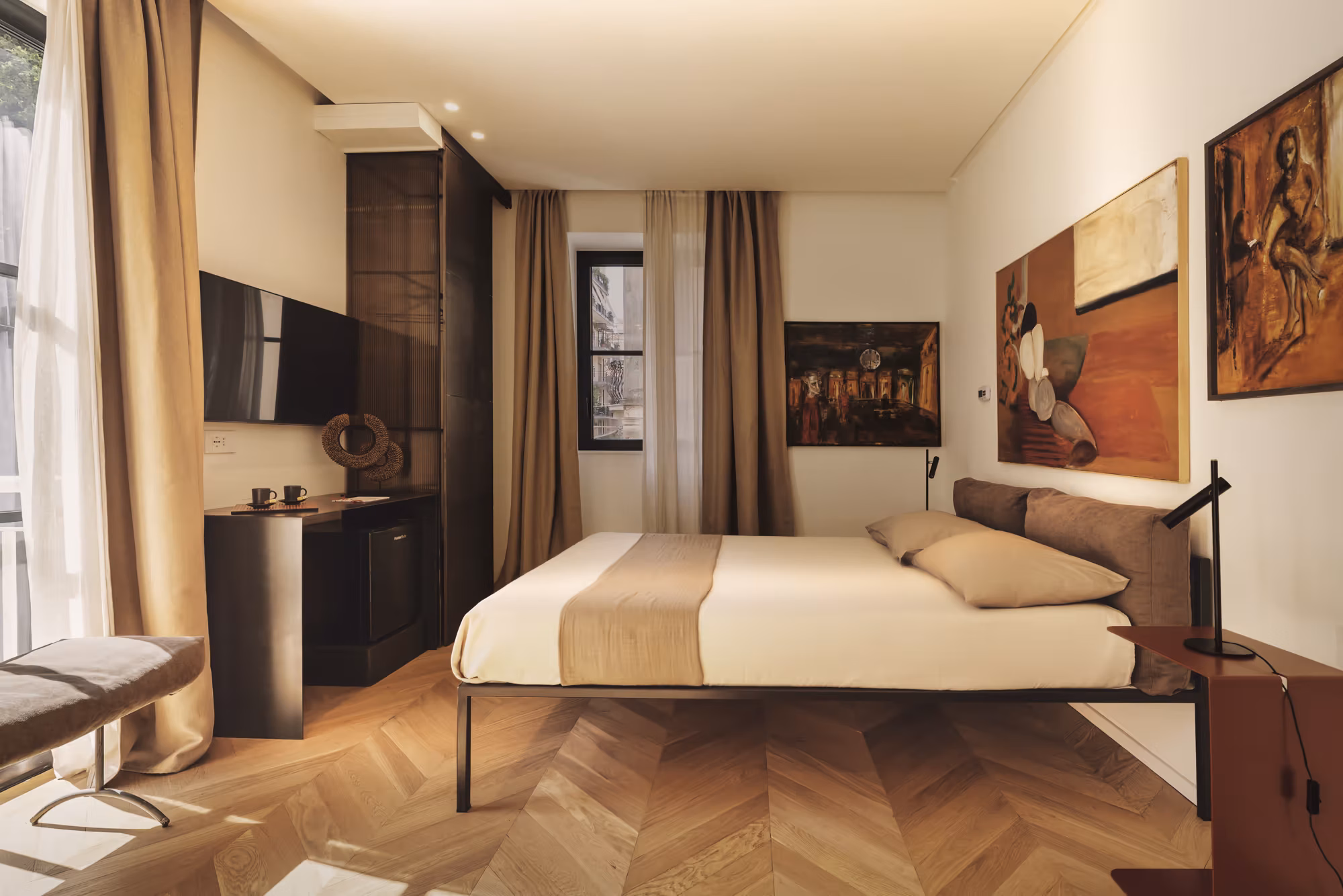Camera luminosa con parquet a spina di pesce, letto matrimoniale e dipinti alle pareti